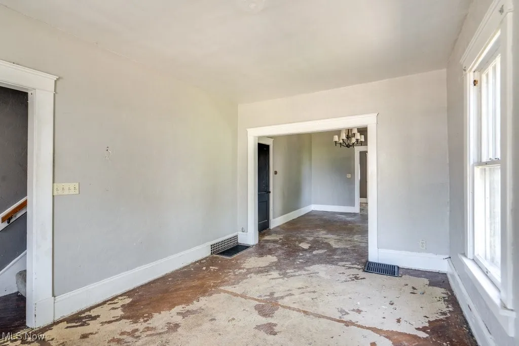 Unfurnished room featuring baseboards and a chandelier