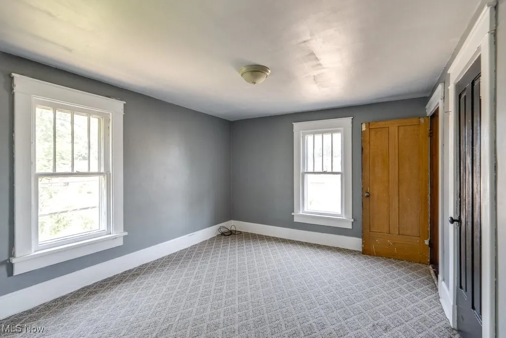 Unfurnished room with baseboards and light carpet