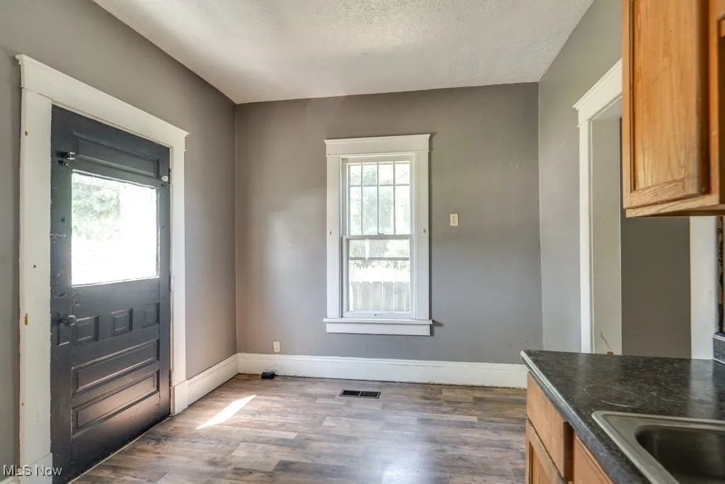 Unfurnished dining area featuring wood finished floors, plenty of natural light, and a textured ceiling
