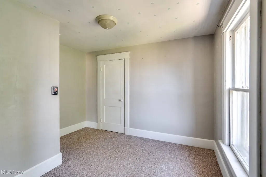 Spare room with light carpet and baseboards