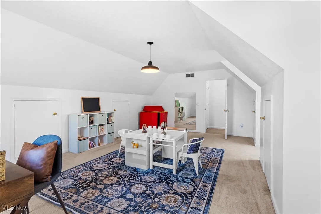 Recreation room with lofted ceiling and light colored carpet