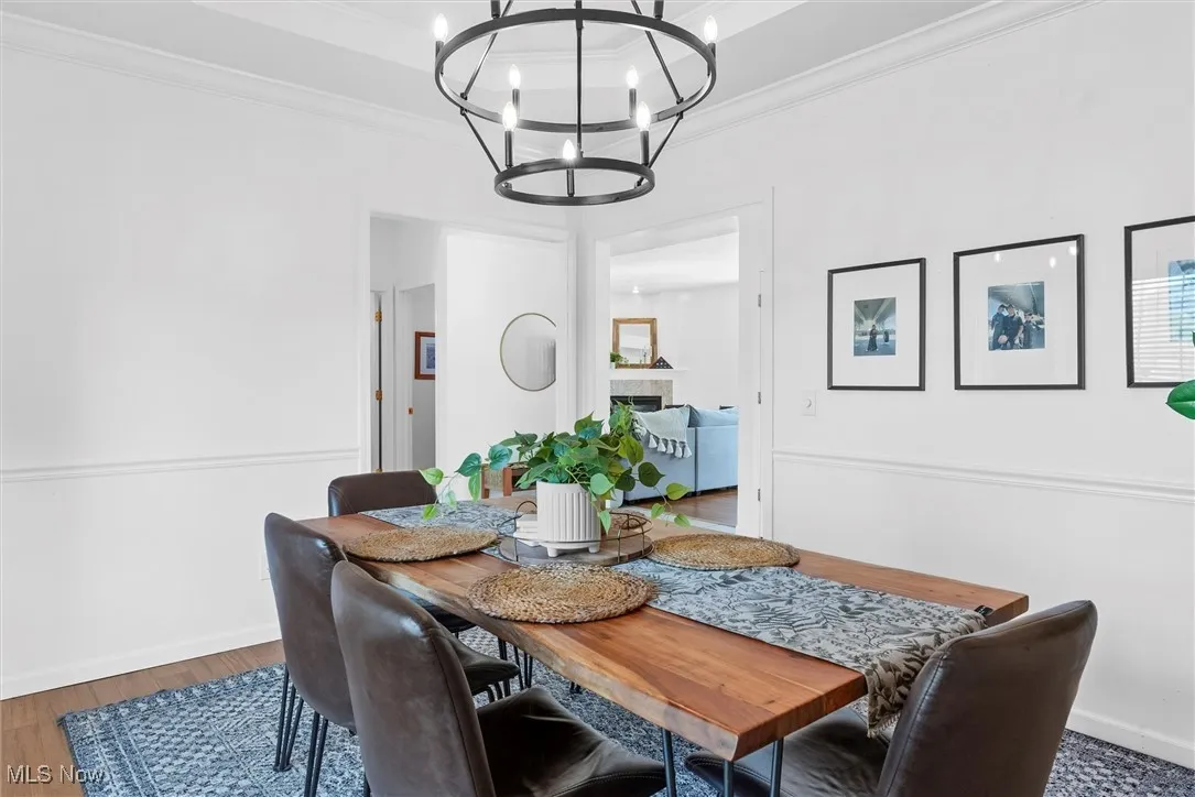 Dining area with a chandelier, crown molding, a tiled fireplace, and wood finished floors