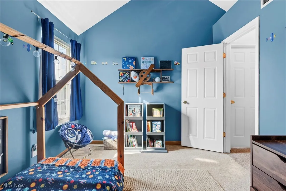 Carpeted bedroom with lofted ceiling and baseboards