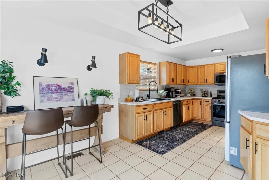Kitchen with appliances with stainless steel finishes, light countertops, tasteful backsplash, and light tile patterned floors
