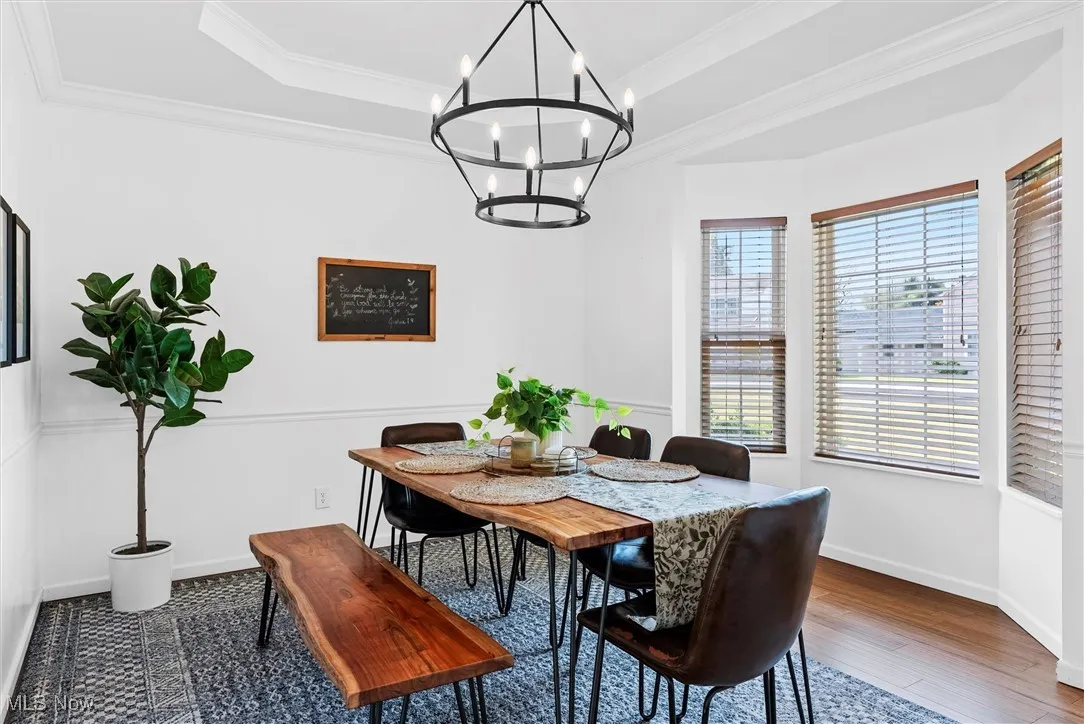 Dining room with a chandelier, ornamental molding, a tray ceiling, and wood finished floors