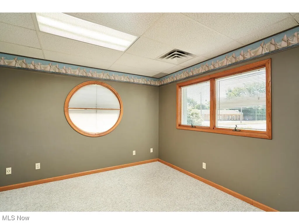 Unfurnished room with carpet flooring and a drop ceiling