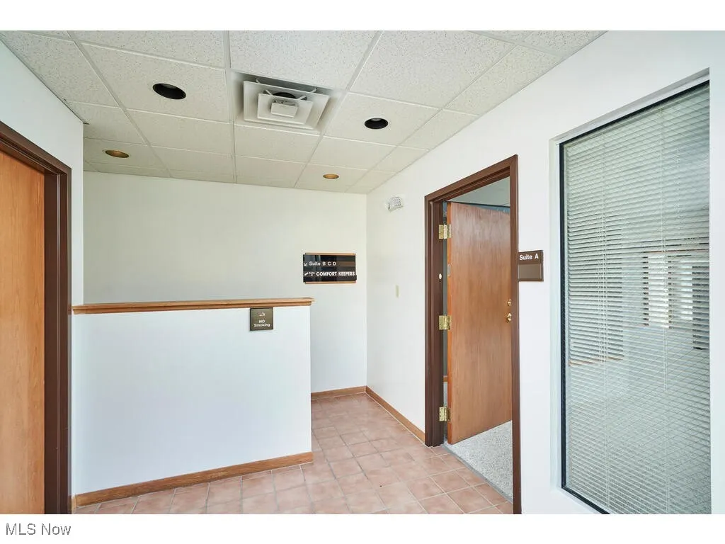 Hallway featuring light tile floors and a drop ceiling