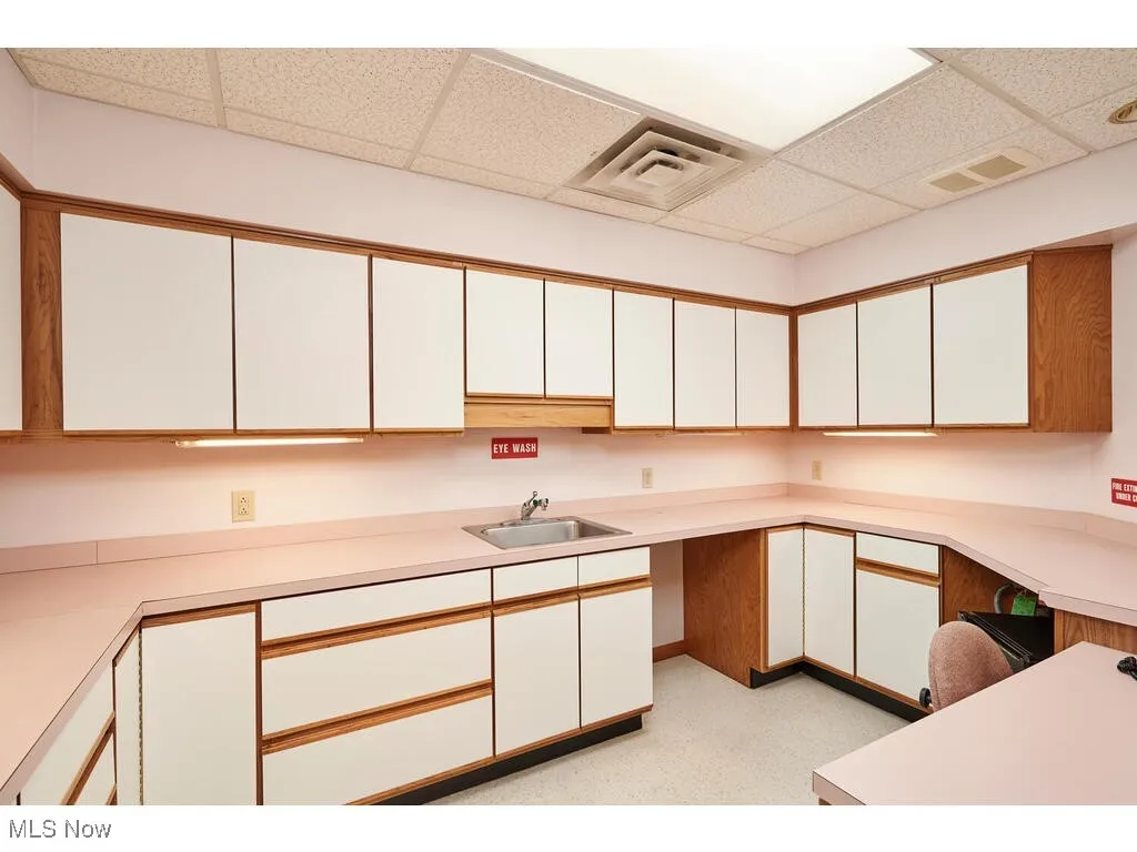 Kitchen with white cabinetry, sink, and a drop ceiling