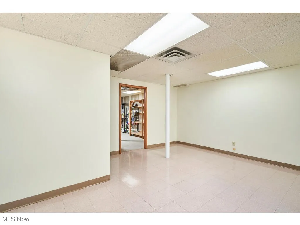 Tiled spare room featuring a drop ceiling
