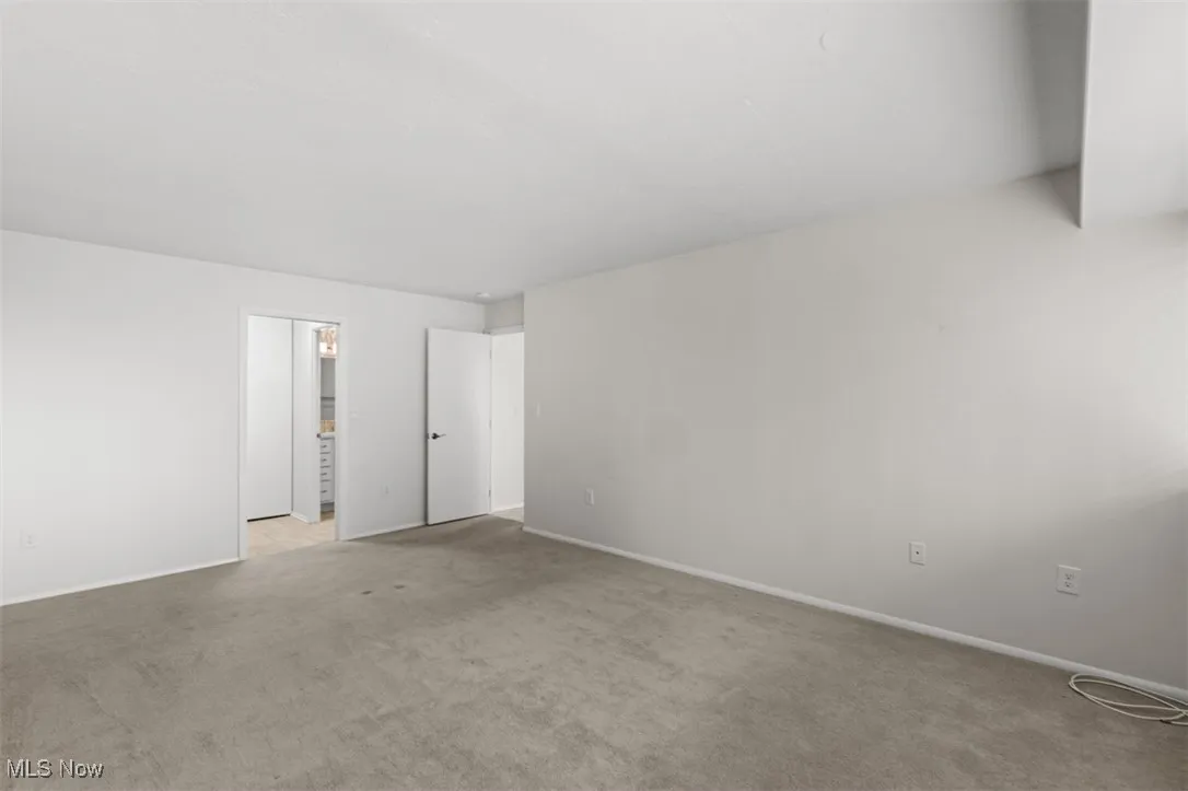 Unfurnished bedroom with light carpet and baseboards