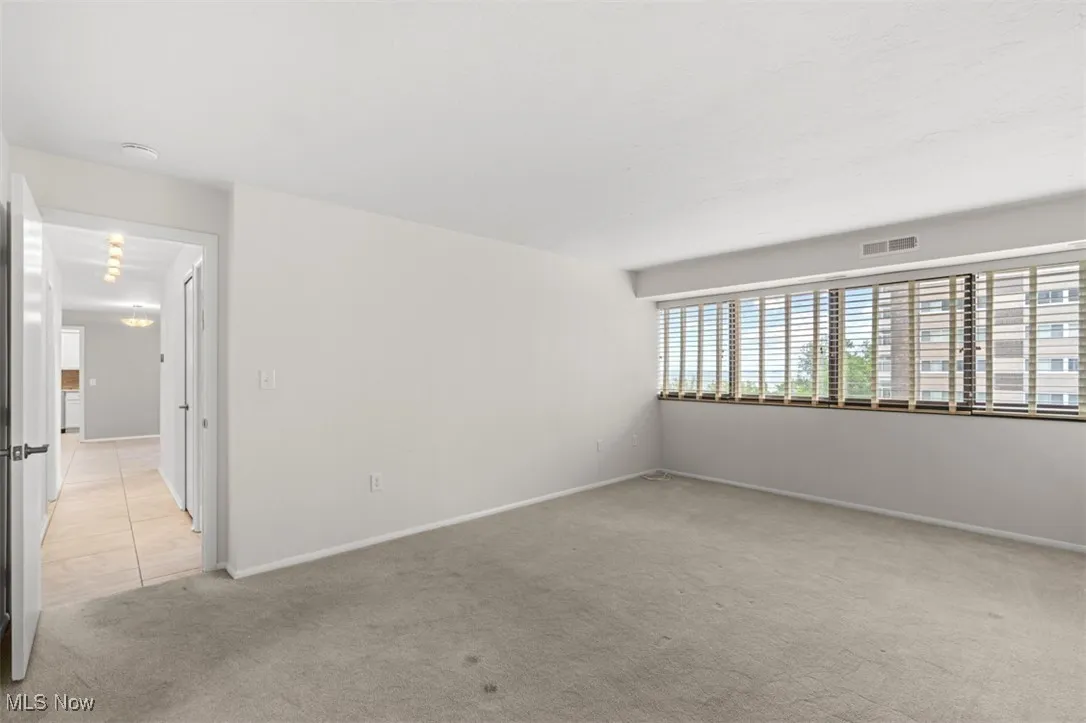 Unfurnished room featuring light carpet and baseboards