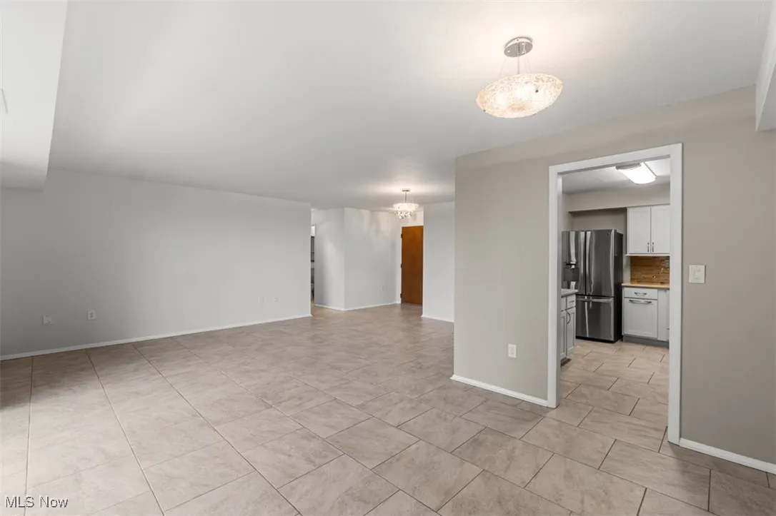 Unfurnished room with baseboards and a chandelier