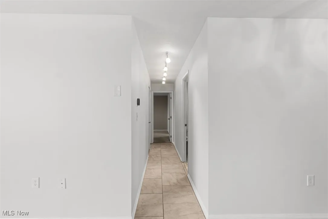 Hall featuring light tile patterned flooring and baseboards