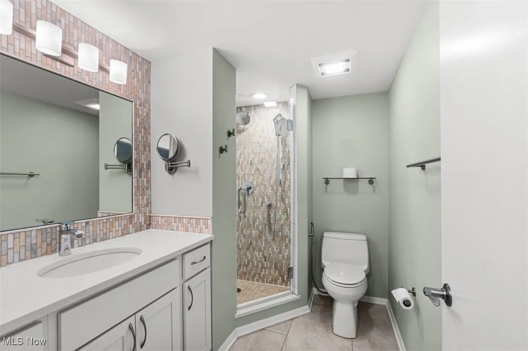 Full bathroom with a stall shower, vanity, and light tile patterned floors