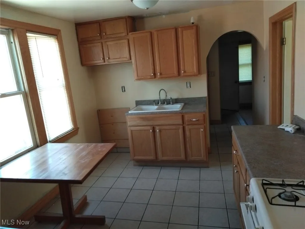 Kitchen with gas range gas stove, arched walkways, and light tile patterned floors