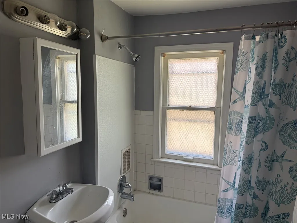 Full bathroom with shower / tub combo with curtain and healthy amount of natural light