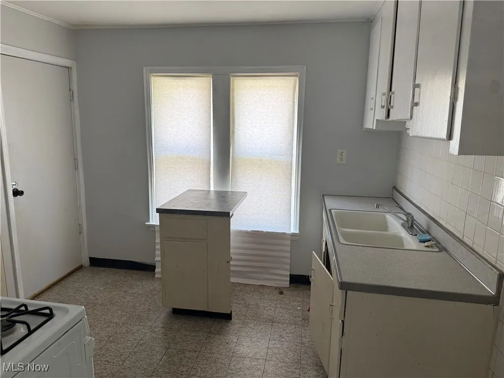 Kitchen with light floors, gas range gas stove, and white cabinets