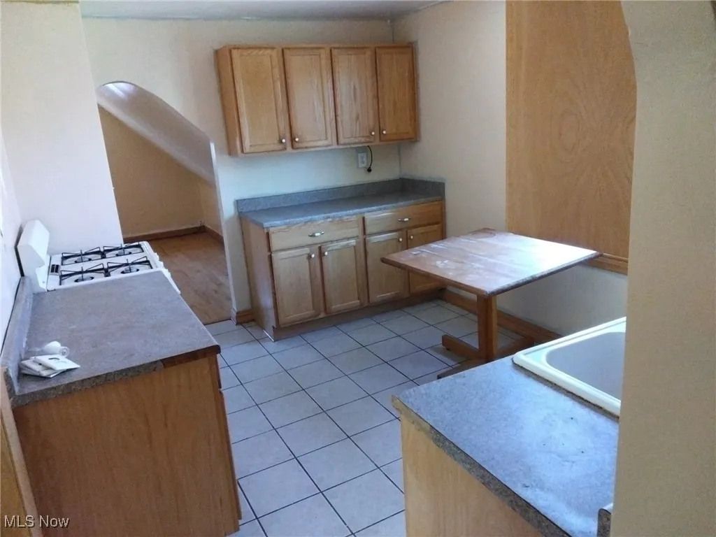 Kitchen featuring light tile patterned flooring, arched walkways, and stove