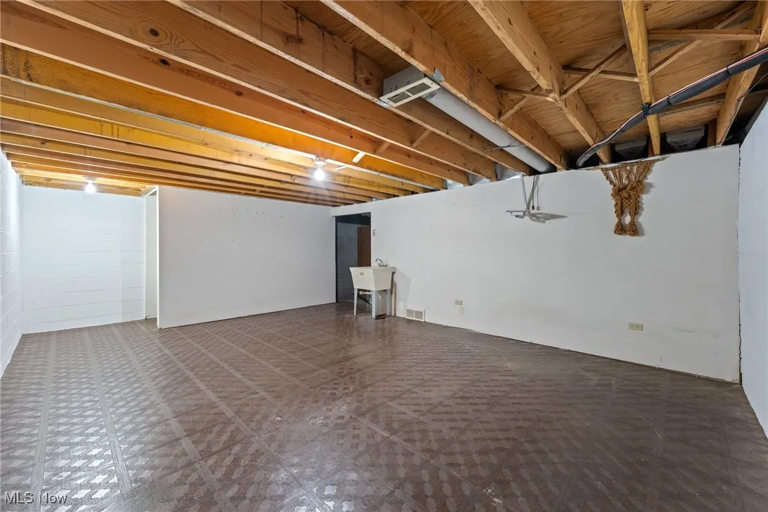 Unfinished below grade area featuring concrete block wall and tile patterned floors