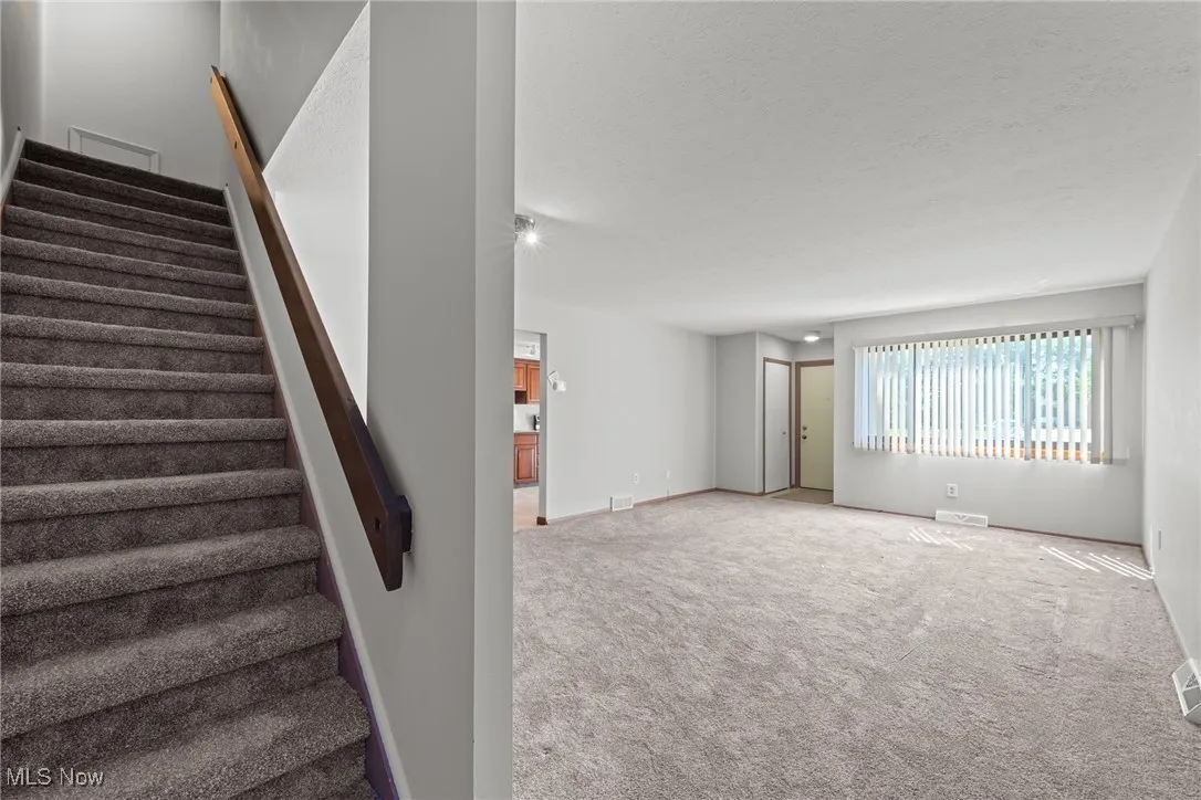Stairway featuring carpet floors and a textured ceiling