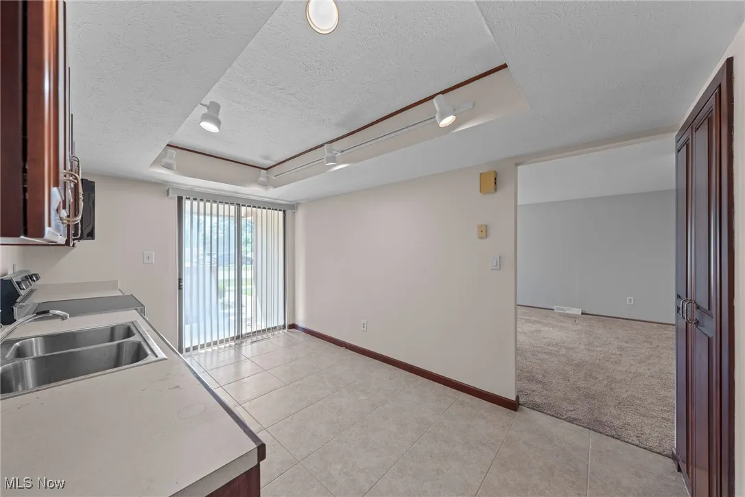 Kitchen featuring light tile patterned flooring, a textured ceiling, open floor plan, rail lighting, and light countertops