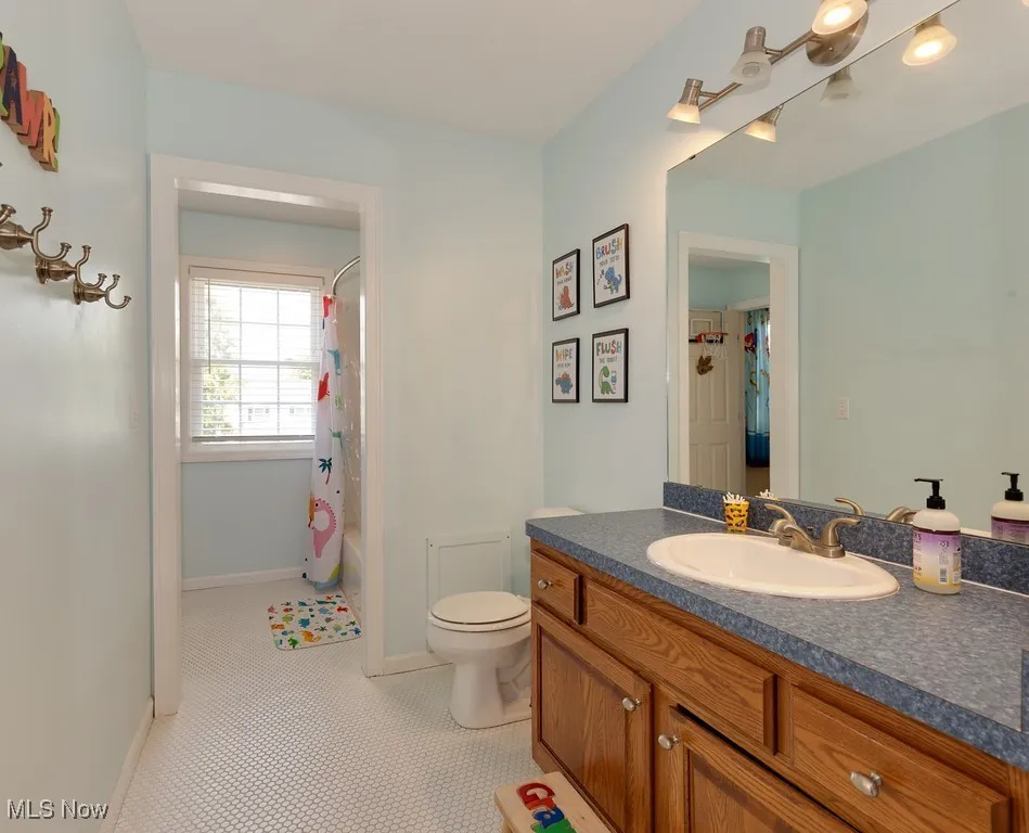Bathroom featuring vanity, shower / bath combination with curtain, and tile patterned floors