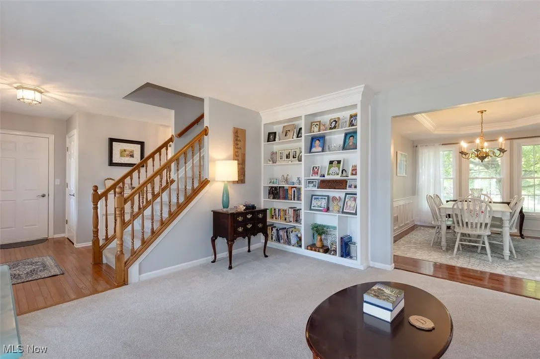 Sitting room featuring carpet, a chandelier, built in shelves, stairway, and wood finished floors