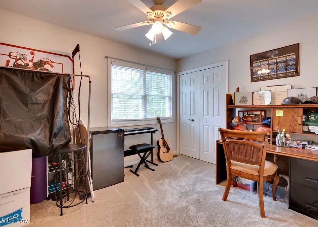 Carpeted home office featuring ceiling fan