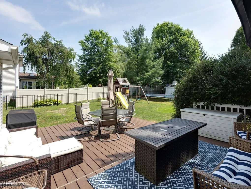 Wooden deck with a trampoline, a playground, and outdoor dining space