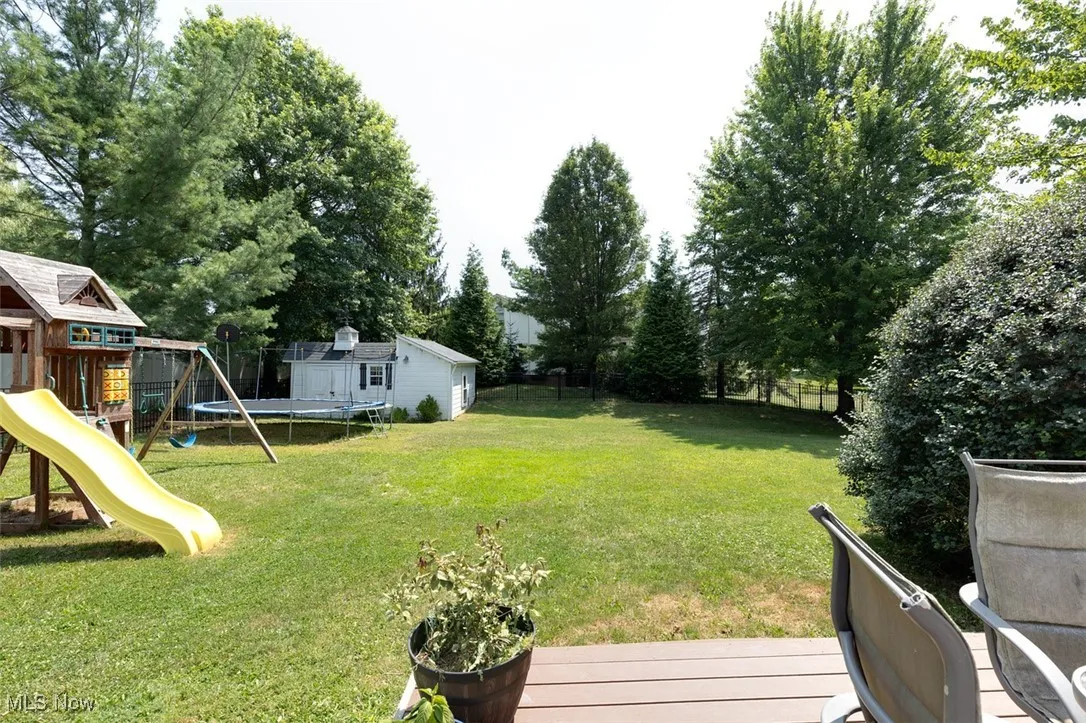 View of yard with a trampoline, a playground, an outbuilding, and a deck