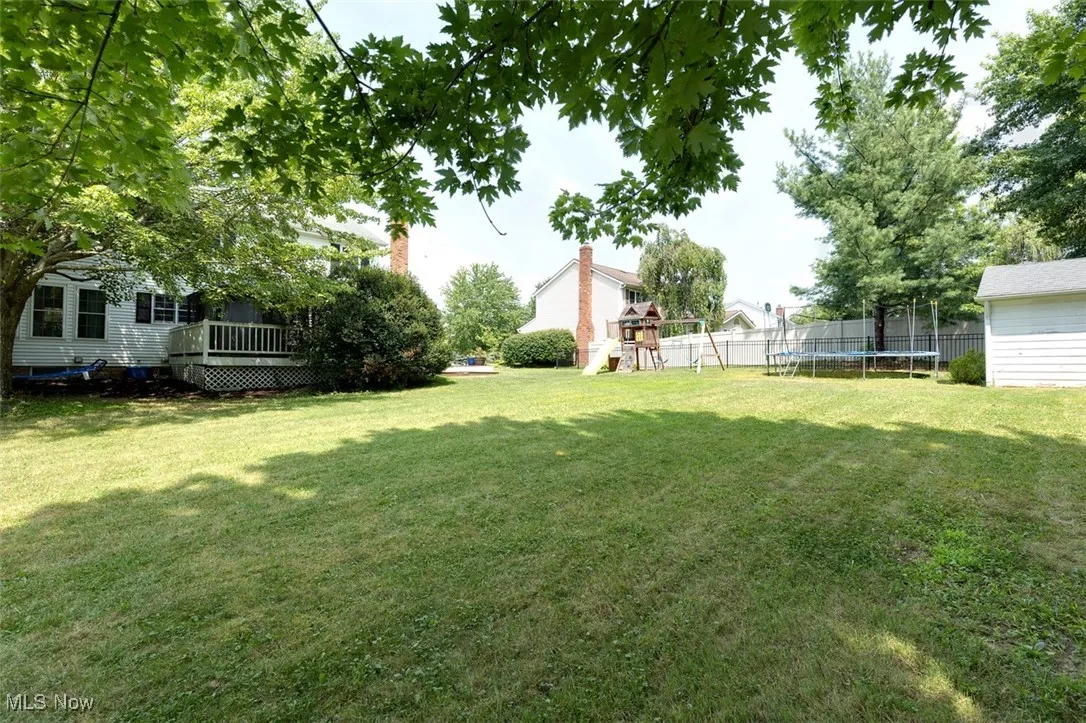 View of yard with a trampoline, a playground, and a deck