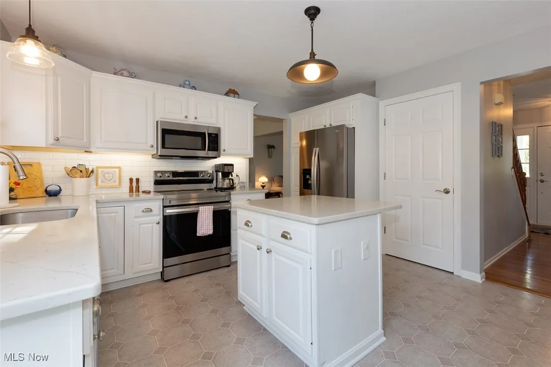 Kitchen with stainless steel appliances, tasteful backsplash, and white cabinets