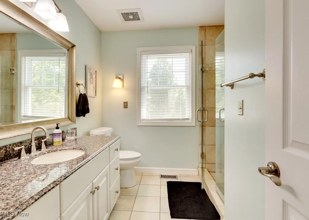 Full bath featuring vanity, tile patterned floors, and a stall shower