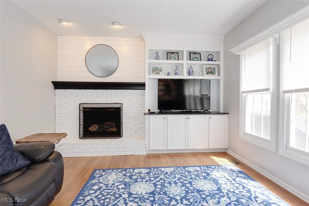 Living room with light wood-style floors and a brick fireplace