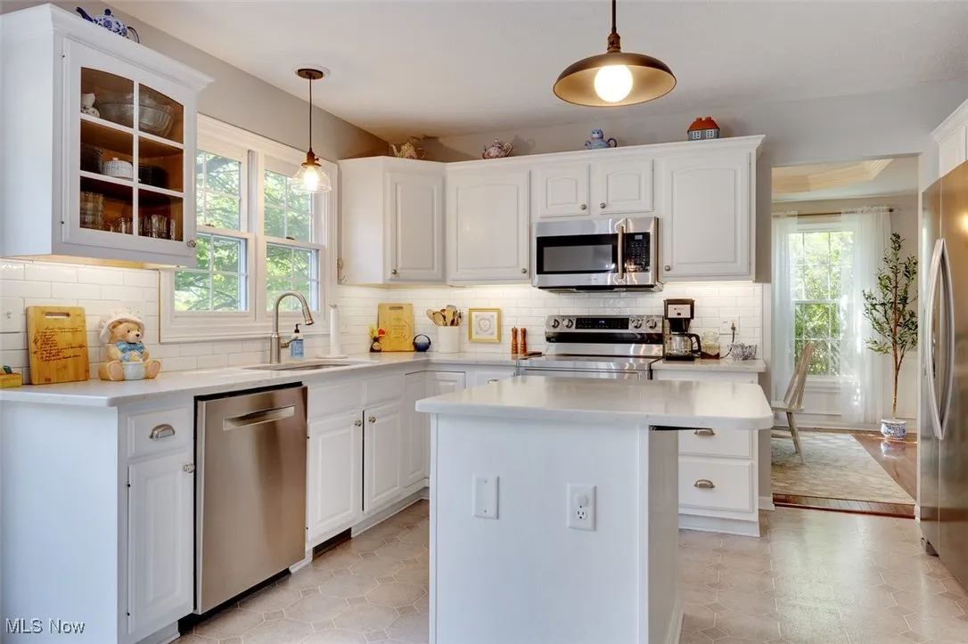 Kitchen featuring stainless steel appliances, light countertops, plenty of natural light, and white cabinets