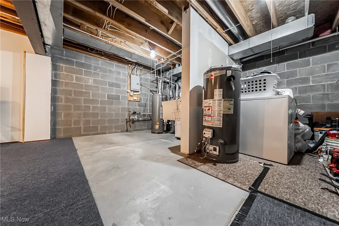 Unfinished basement featuring water heater and separate washer and dryer