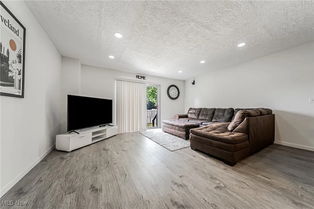 Living area with a textured ceiling, recessed lighting, and wood finished floors