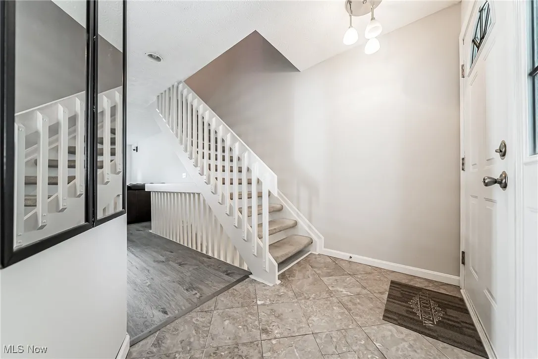Foyer entrance featuring stairway and baseboards
