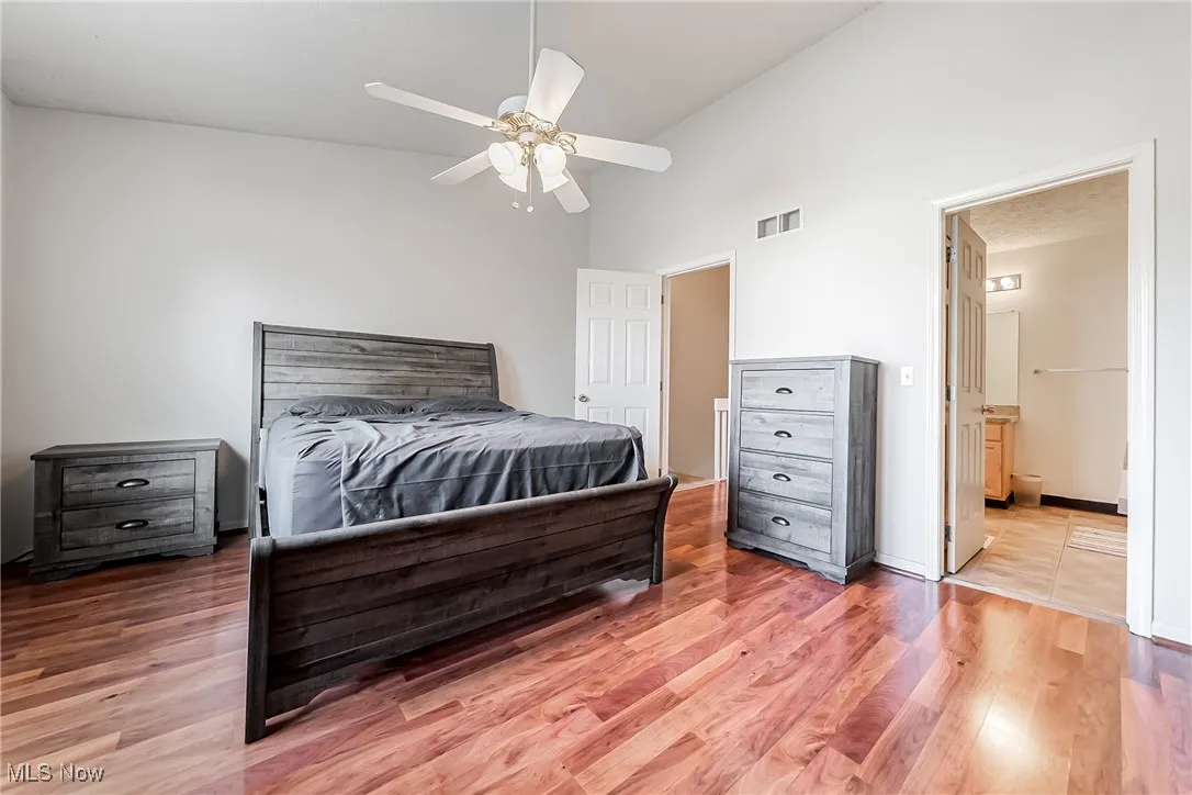 Bedroom with light wood-style flooring, high vaulted ceiling, a ceiling fan, and ensuite bathroom