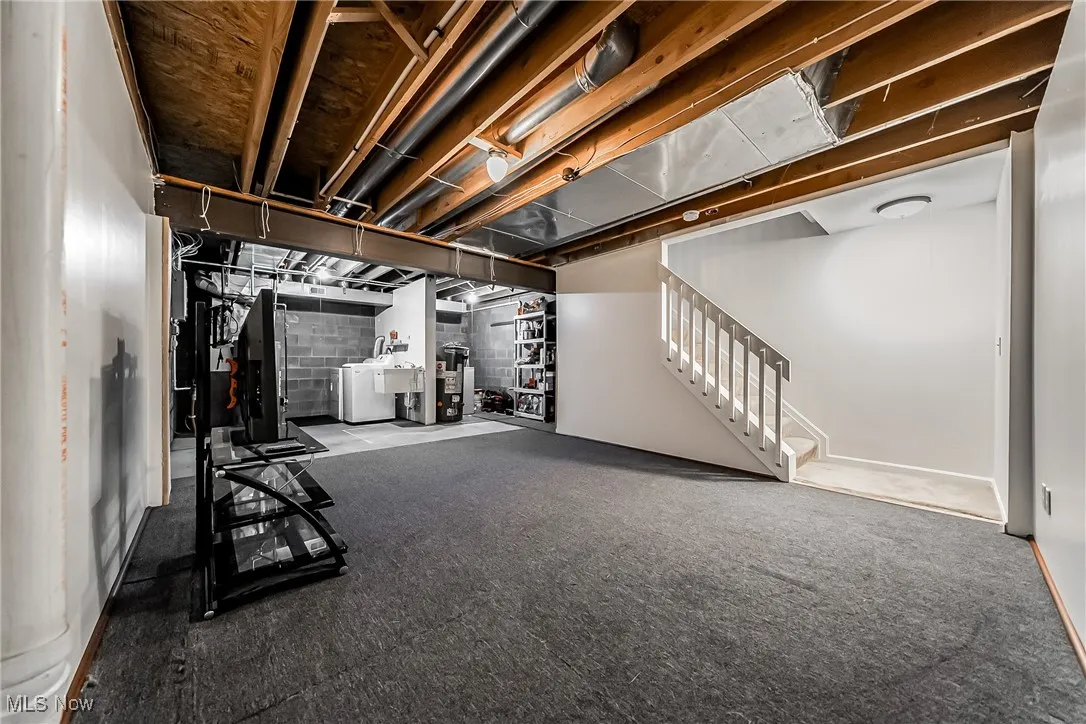 Below grade area with stairway, concrete block wall, and washer and dryer