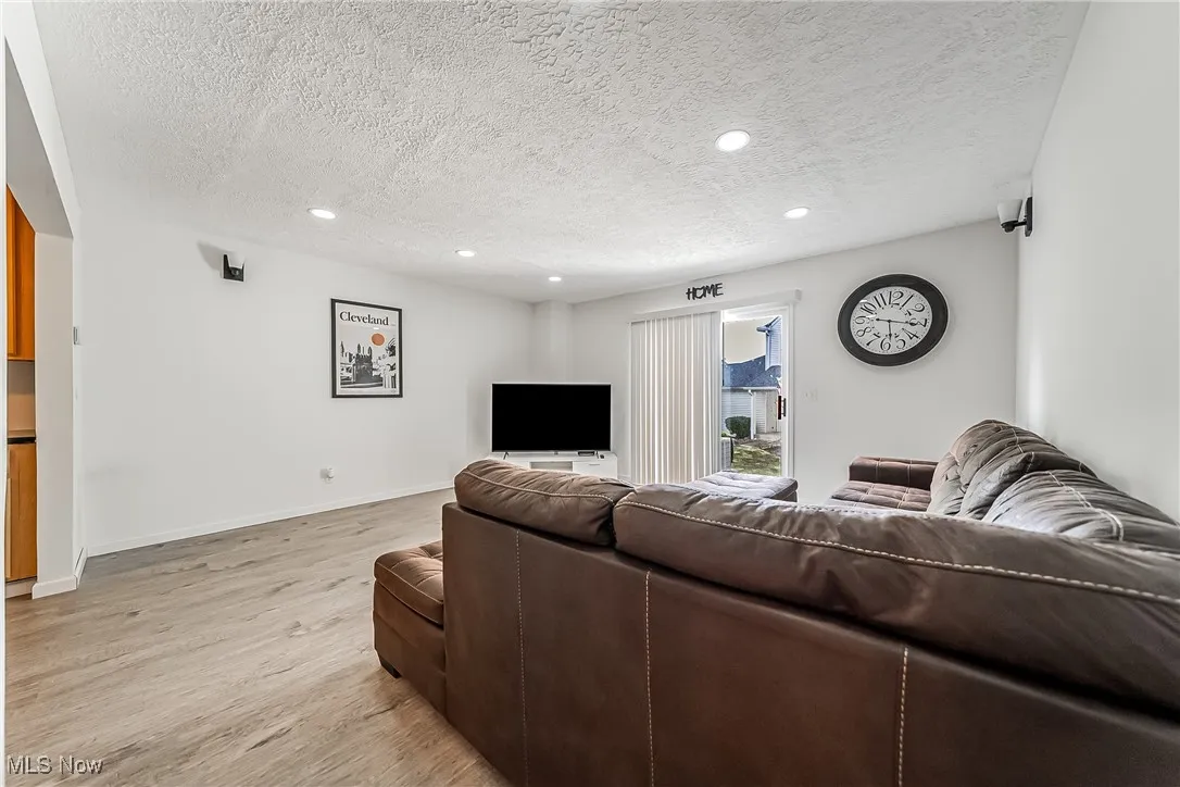 Living area with light wood-type flooring, recessed lighting, and a textured ceiling