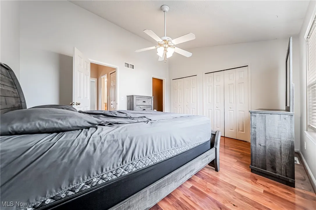 Bedroom with vaulted ceiling, wood finished floors, multiple closets, and a ceiling fan