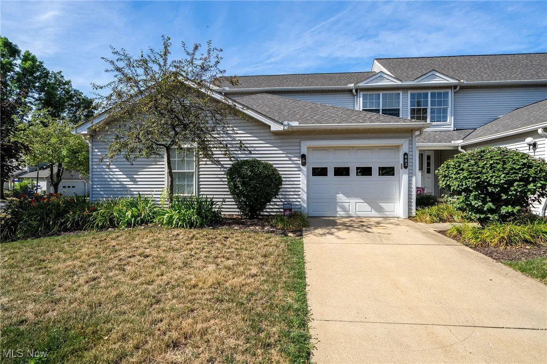 Traditional-style house with a garage, driveway, a front lawn, and a shingled roof