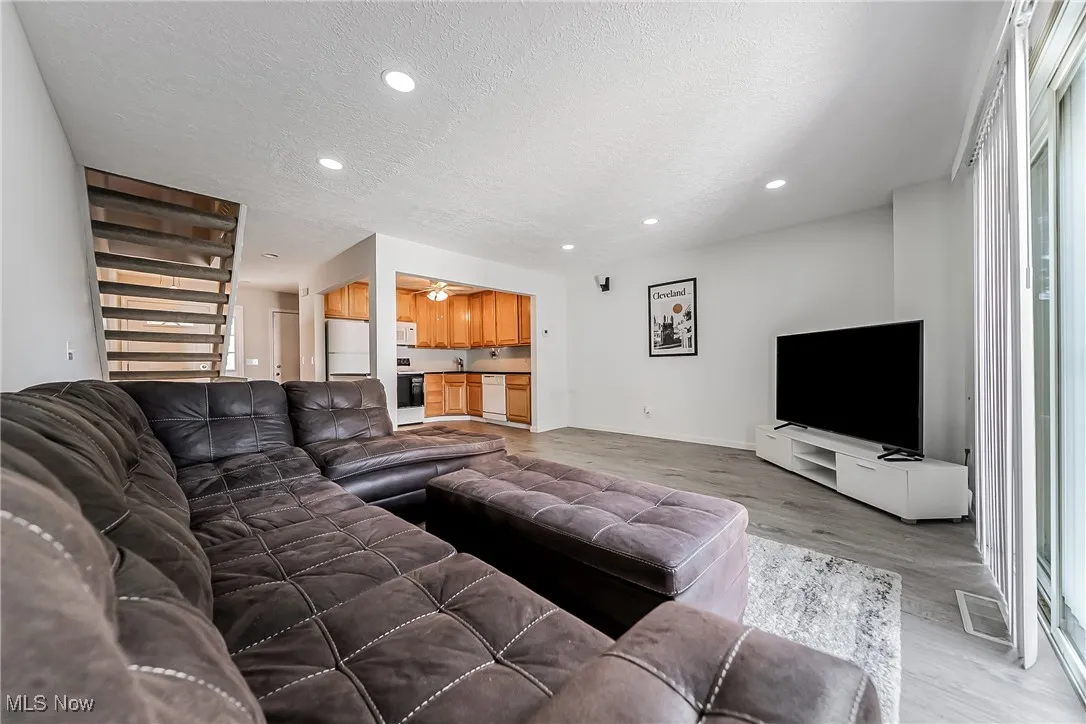 Living room with light wood-style flooring, a textured ceiling, recessed lighting, and ceiling fan