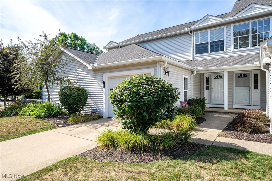 View of front of home featuring an attached garage, roof with shingles, and concrete driveway