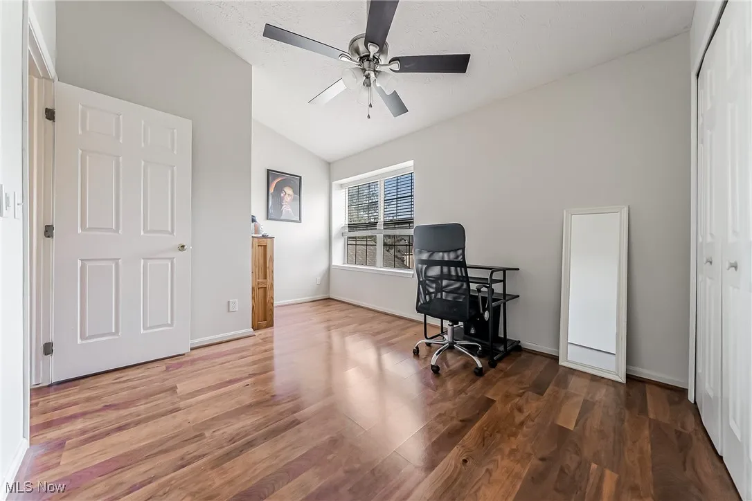 Office with vaulted ceiling, wood finished floors, ceiling fan, and a textured ceiling