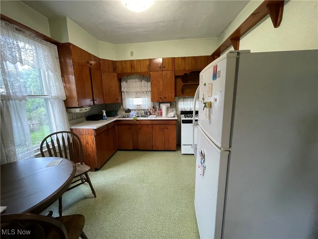 Kitchen featuring white appliances, brown cabinets, light countertops.
