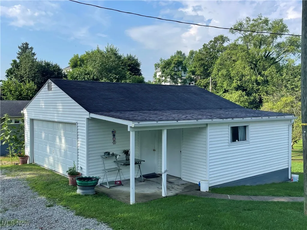 view of 2 car garage with attached shed and patio area