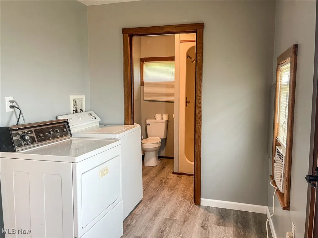 Washroom with washing machine and dryer, healthy amount of natural light, and light wood-style flooring