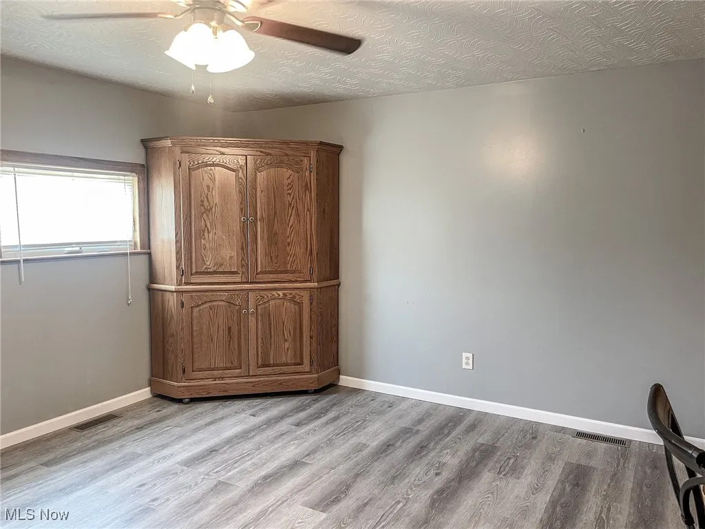 Unfurnished bedroom with a textured ceiling, light wood-type flooring, and ceiling fan
